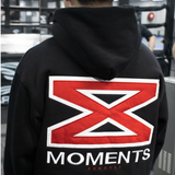 Black MMA hoodie with a red and white logo on the back, worn by a person in an indoor setting.